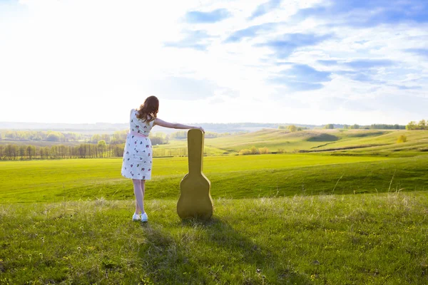 Woman walking in green field with acoustic Guitar — Stock Photo, Image