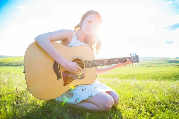 Landmädchen sitzt mit Akustikgitarre auf Feld — Stockfoto