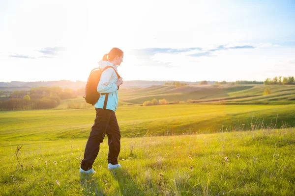 Junge Frau mit Rucksack auf einem Feld. — Stockfoto