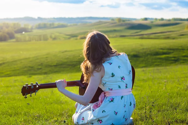 Landmädchen sitzt mit Akustikgitarre auf Feld — Stockfoto