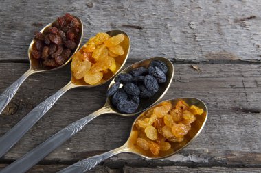 Kuru üzümler ahşap masada metal kaşıklarda