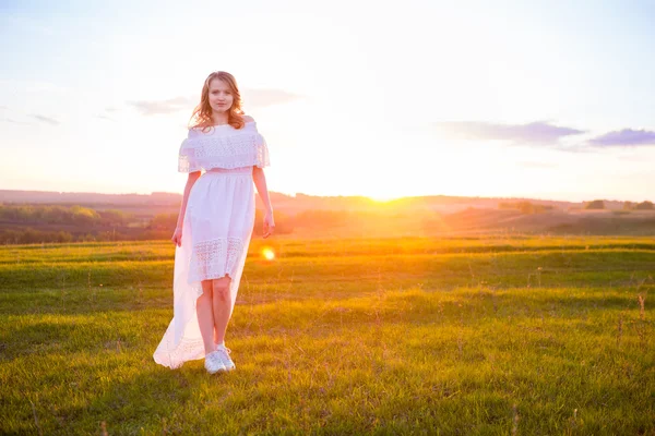 Девушка на открытом воздухе наслаждается природой. Женщина в белом платье на поле — стоковое фото