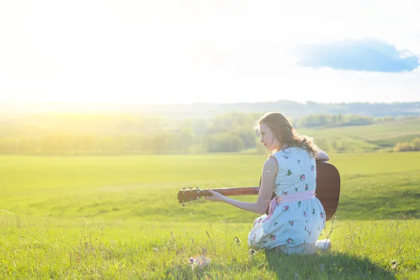 Landmädchen sitzt mit Akustikgitarre auf Feld — Stockfoto