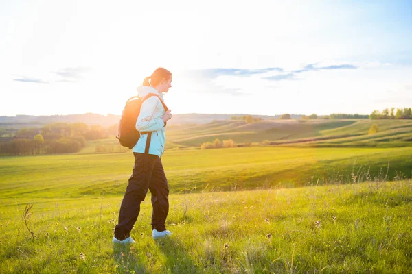 Junge Frau mit Rucksack auf einem Feld. — Stockfoto