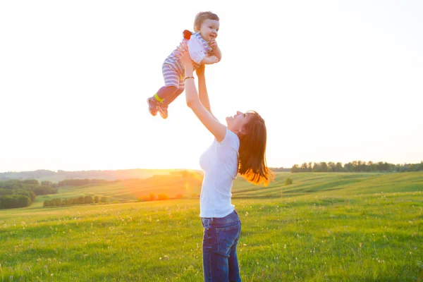 Mother and her child playing in spring field — Stock Photo, Image