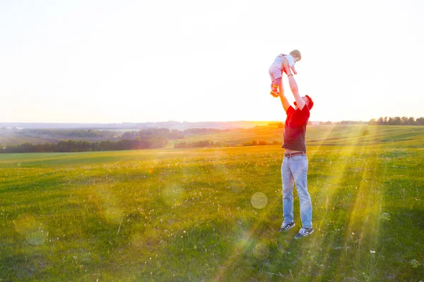 Happy father holding kid in arms, throwing baby in air. — Stock Photo, Image