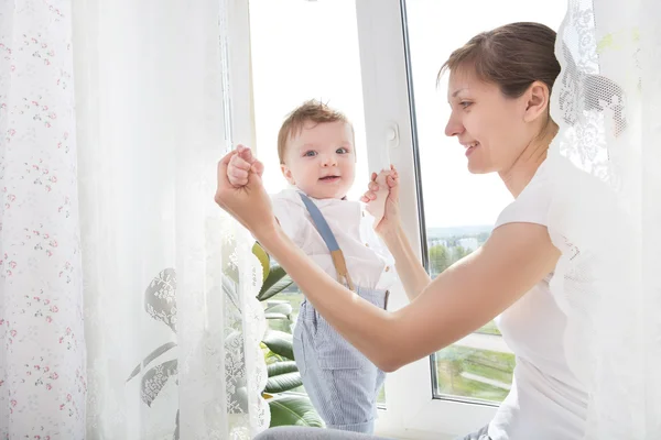 Newborn baby in tender embrace of mother at the window — Stock Photo, Image