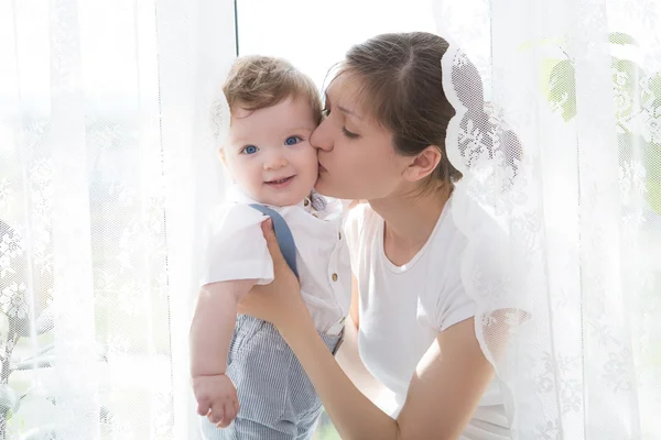 Noworodek w przetargu objęciach matki w oknie — Zdjęcie stockowe