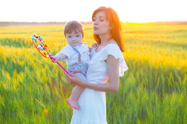 幸せな母親を保持赤ちゃん笑顔上の小麦畑で日光. — ストック写真