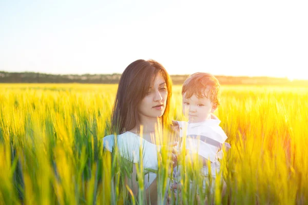 Pretty mom give a hug to her baby in field — Stock Photo, Image