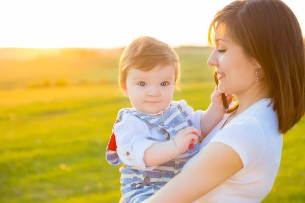 Bella giovane donna con bambino sul tramonto estivo . — Foto Stock