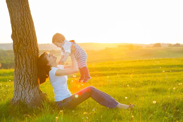 Schöne junge Frau mit Junge auf der Gänseblümchenwiese. — Stockfoto