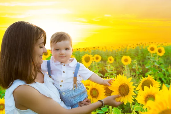 Famiglia felice con girasoli divertirsi all'aperto nel campo estivo — Foto Stock