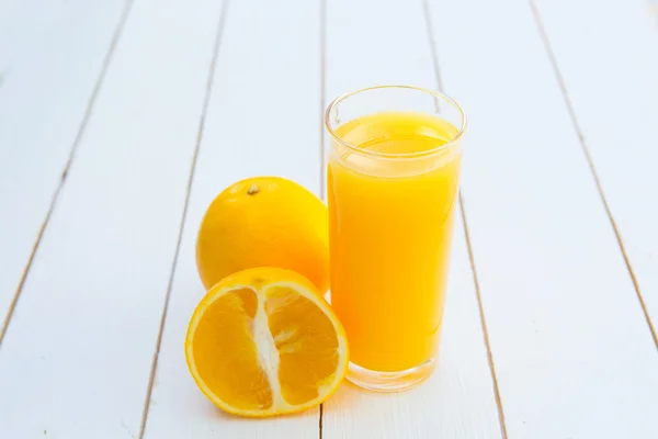 Ποτήρι φρεσκοστυμμένου χυμού πορτοκαλιού σε ξύλινο τραπέζι — Φωτογραφία Αρχείου
