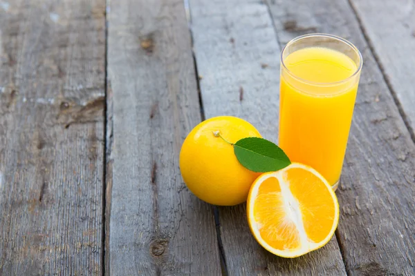 Vaso de zumo de naranja recién prensado sobre mesa de madera —  Fotos de Stock