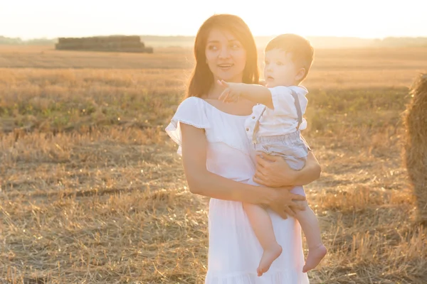 Mère et fils. Foin pile ou balle sur champ jaune . — Photo