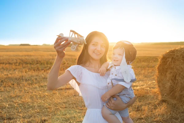 Щаслива дитина і жінка грають з іграшковим літаком проти поля . — стокове фото