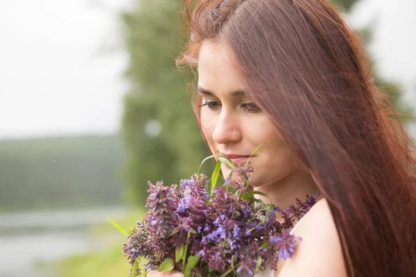 Mädchen mit Wildblumen auf Feld bei bewölktem Tag — Stockfoto