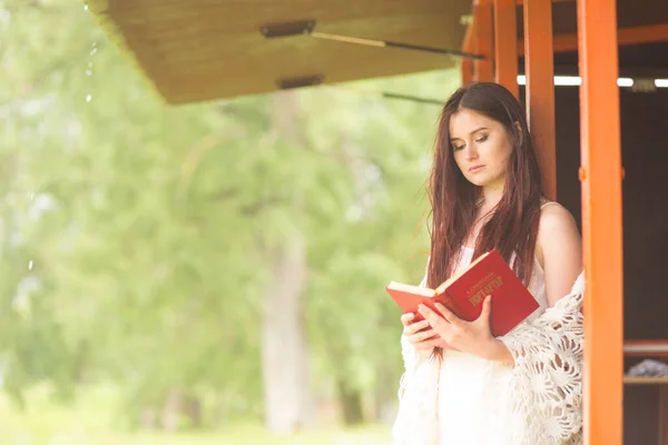 Una mujer guapa con vestido blanco leyó el libro. Chica se sienta en la terraza — Foto de Stock