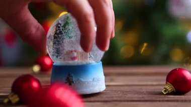 Noel ağacının arka planında Noel ışıkları olan kar küresi