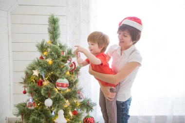 Anne ve oğlu birlikte Noel ağacı süslüyorlar, çiftlik evi tasarımı.