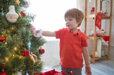Evdeki Noel ağacını süsleyen küçük çocuk.