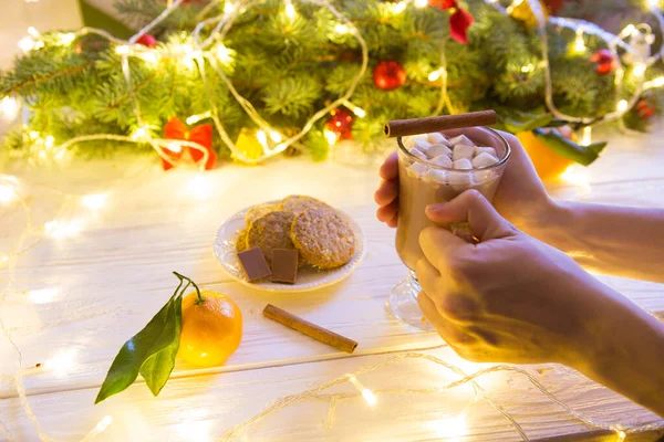 Frau reicht Tasse heiße Schokolade auf Christbaumhintergrund — Stockfoto