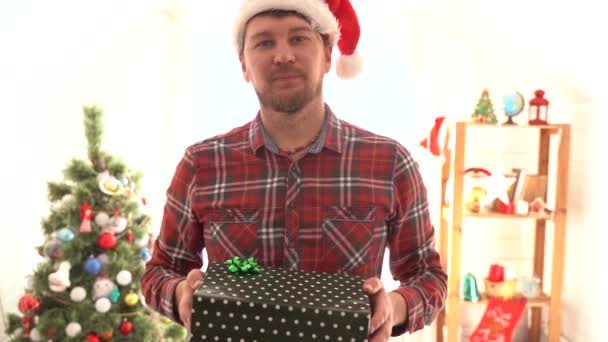 Um homem de camisa xadrez dá um presente de Natal — Vídeo de Stock