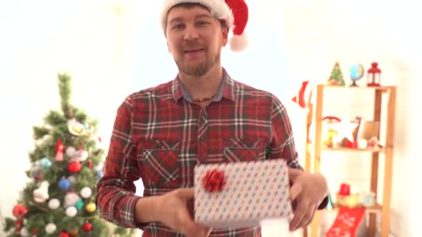 Un hombre con una camisa a cuadros da un regalo de Navidad — Vídeo de stock