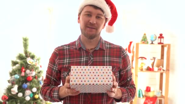 Un hombre con una camisa a cuadros da un regalo de Navidad — Vídeo de stock