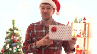 Ekose gömlekli bir adam Noel hediyesi verir.
