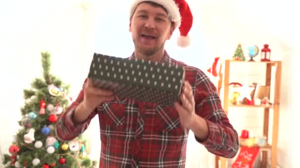 Um homem de camisa xadrez dá um presente de Natal — Vídeo de Stock
