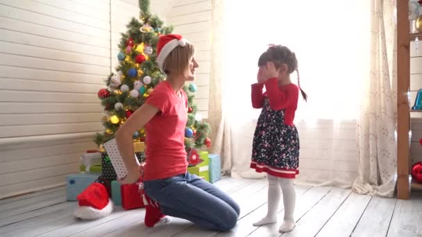 Mom gives daughter a Christmas present in a bright sunny room — Stock Video