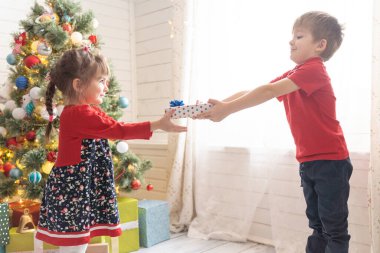 Oğlan, COVID-19 salgınından dolayı kıza sosyal mesafede Noel hediyesi veriyor.