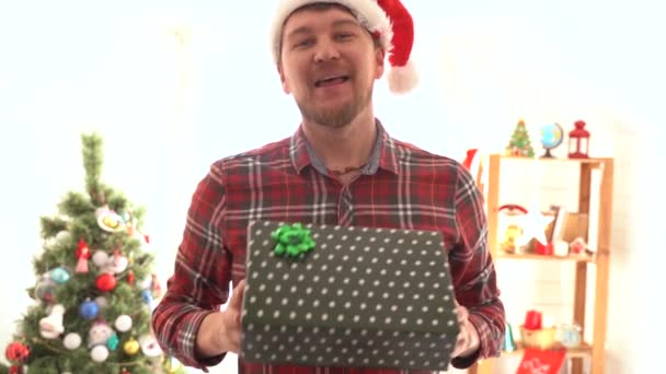 Um homem de camisa xadrez dá um presente de Natal — Vídeo de Stock
