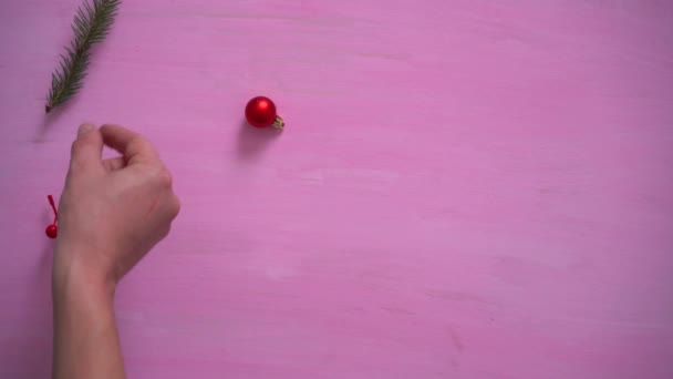 Мандарины вручную наполняют розовый фон фиолетовыми ветвями, бузины и шариками. — стоковое видео
