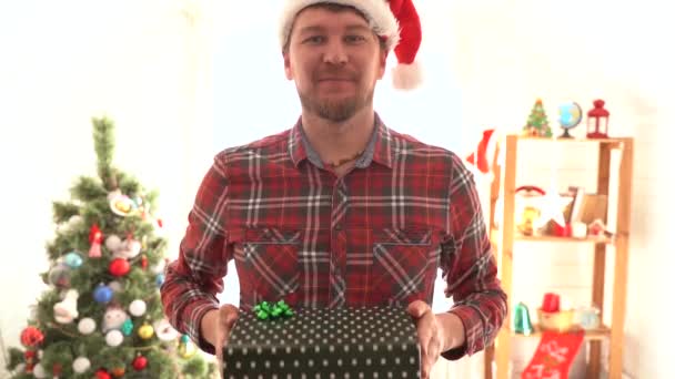 Egy férfi kockás ingben karácsonyi ajándékot ad. — Stock videók