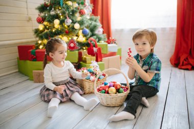 Mutlu kız ve oğlan Noel kışında güneşli bir sabahta süslü bir Noel kutlaması odasında Noel ağacı ve hediyelerle