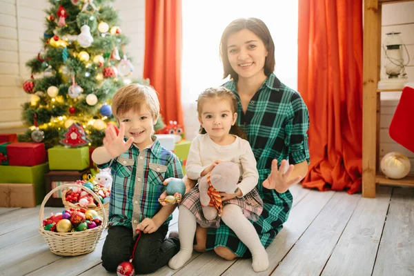 Mutlu aile annesi, oğlu ve kızı Noel kışında güneşli bir sabahta süslü bir Noel kutlaması odasında Noel ağacı ve hediyelerle — Stok fotoğraf