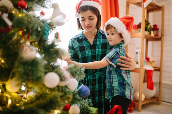 Feliz familia mamá e hijo en una mañana soleada de invierno de Navidad en una sala de celebración de Navidad decorada con un árbol de Navidad y regalos —  Fotos de Stock