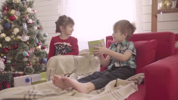 Little boy give to girl a Christmas present in a bright sunny room. Slow motion — Stockvideo