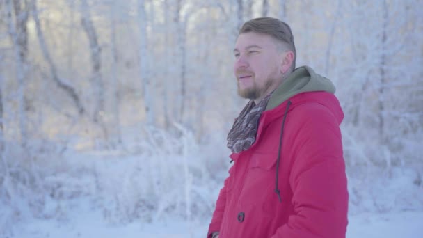 En man går genom en vinterskog med snötäckta träd på en vacker frostig morgon — Stockvideo