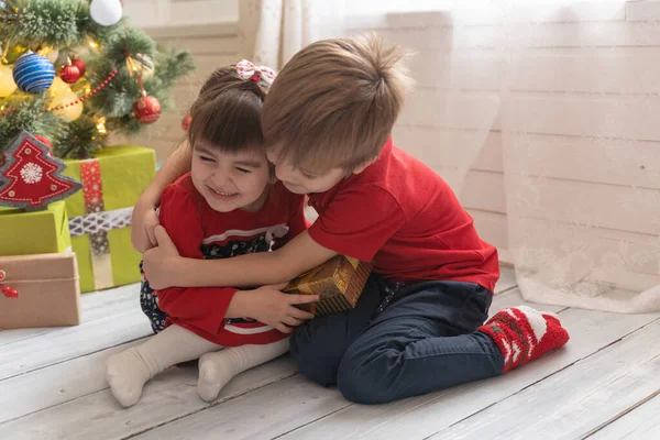 Oğlan, parlak güneşli bir odada bir kıza Noel hediyesi verir. — Stok fotoğraf