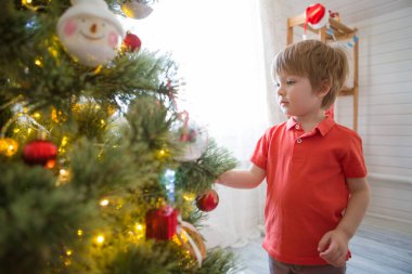Evdeki Noel ağacını süsleyen küçük çocuk.