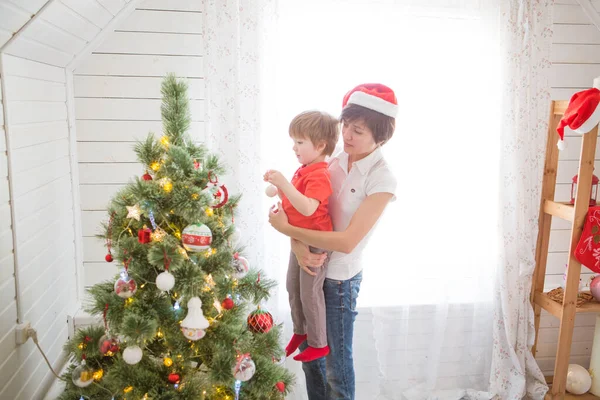 Madre con su hijo decorando el árbol de Navidad juntos, diseño de la casa de la granja —  Fotos de Stock