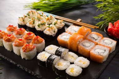 Siyah arka planda wasabi ve zencefilli suşi ruloları. Japon Doğu mutfağı.