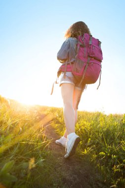 Sınırları olmayan bir dünya. Dağlardaki kızın çarpıcı yolculuğu. Açık havada, kestane rengi taytlı ve gri spor ayakkabılı ince kadın bacakları orman yolu boyunca uzanıyor. Yaşam biçimi