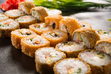 Siyah arka planda wasabi ve zencefilli fırında suşi ruloları. Japon Doğu mutfağı.