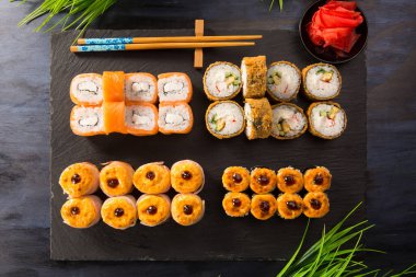 Siyah arka planda wasabi ve zencefilli fırında suşi ruloları. Japon Doğu mutfağı.