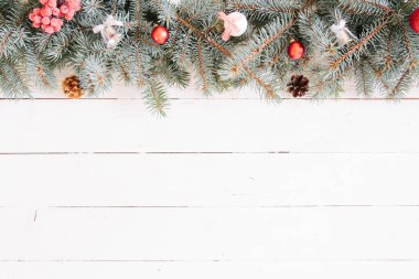 Bulanık Noel arkaplanı, köknar dalları, peri ışıkları ve beyaz tahta üzerinde noel süslemeleri.